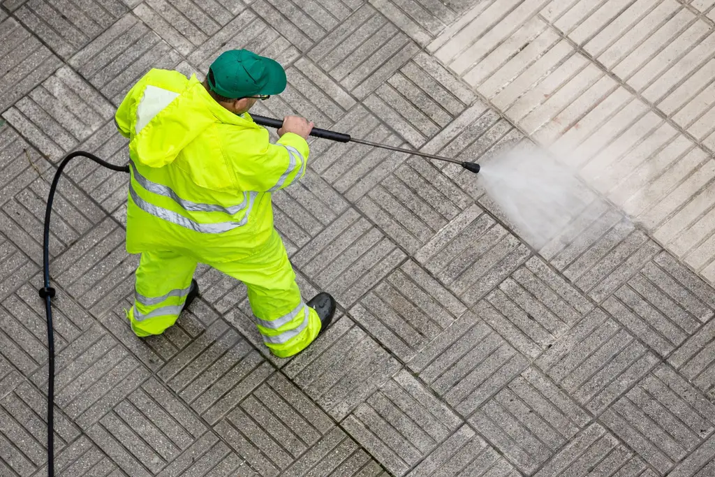 Professional driveway cleaning on residential property with high-pressure equipment
